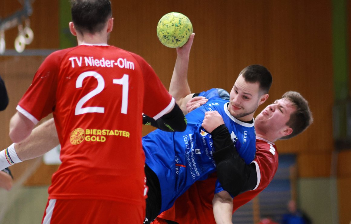 Im Hinrundenvergleich in Nieder-Olm hatte der TVN (r. Denis Milosavljevic) den Sportfreunden Budenheim beim 27:33 den Sportfreunden Budenheim (Mitte: Justus Tessnow) nicht genügend entgegenzustellen. Das soll diesmal anders aussehen, so der Plan der Gäste im Derby.